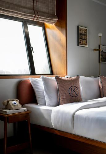 a bed in a room with windows and a telephone at The Kin Hotel in Mumbai