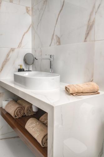 a white bathroom with a sink and towels at Oasis By The Sea - Cyprus in Larnaca