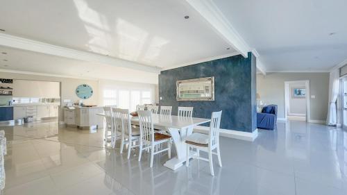 a dining room with a white table and chairs at Die Lig-Huis Struisbaai in Struisbaai