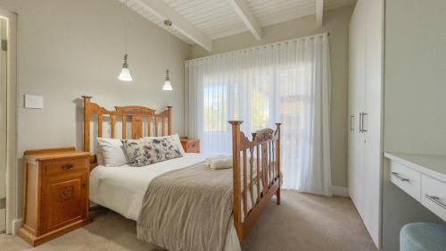 a bedroom with a wooden bed and a window at Die Lig-Huis Struisbaai in Struisbaai