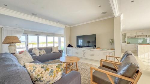 a living room with a couch and a tv at Die Lig-Huis Struisbaai in Struisbaai