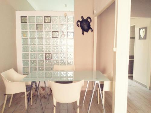une salle à manger avec une table en verre et des chaises blanches dans l'établissement Joli 2 pièces à 2 min de la plage, à Nice