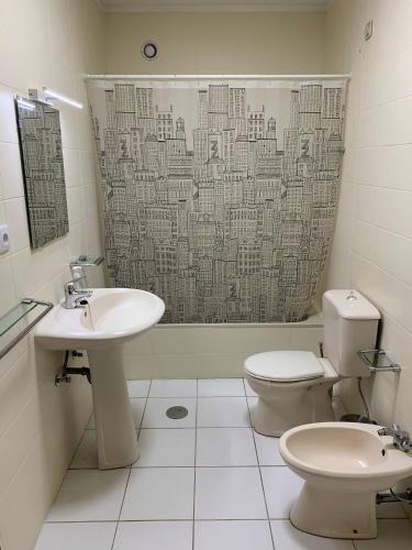 a bathroom with a sink and a toilet and a shower curtain at Madorninha Urban Nest in Porto