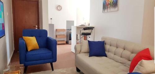 a living room with a couch and a blue chair at Beautiful One Bed & Parlour with Playstation 4, Wi-Fi, Netflix, kitchen, Supermarket, Pharmacy & Laundry in Ankuru