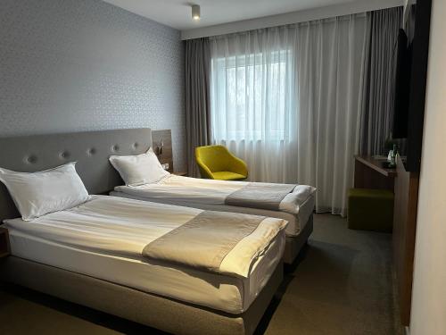 Pokój hotelowy z łóżkiem i żółtym krzesłem w obiekcie Abton Hotel w Łodzi