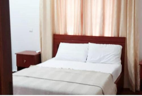 a bedroom with a bed with white sheets and a window at Beautiful One Bed & Parlour with Playstation 4, Wi-Fi, Netflix, kitchen, Supermarket, Pharmacy & Laundry in Ankuru