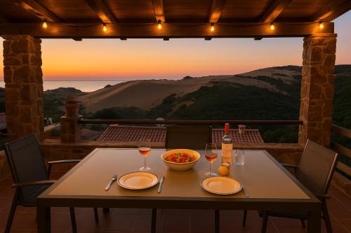a table with two glasses of wine and a bowl of food at Casa vacanze Sardegna, Torre dei Corsari Costa Verde in Torre Dei Corsari