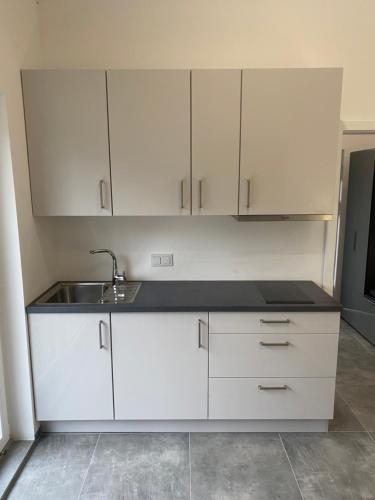 a kitchen with white cabinets and a sink at Villa Aldina Apartment 2 in Bihać