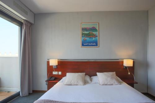 a bedroom with a large bed with white sheets at Hotel Brise de Mer - Piscine intérieure & extérieure in Saint-Raphaël