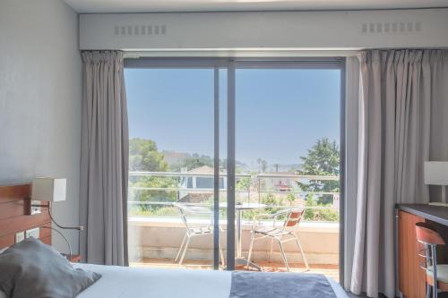 a bedroom with a bed and a view of a balcony at Hotel Brise de Mer - Piscine intérieure & extérieure in Saint-Raphaël