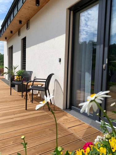 a wooden deck with chairs and flowers on a house at Srnčí vrch in Batňovice