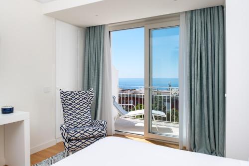 a bedroom with a bed and a chair and a balcony at Pazziella Garden & Suites in Capri