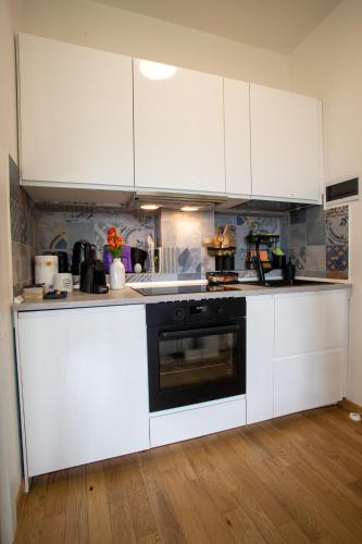 a kitchen with white cabinets and a black oven at HI15 Apartment - Garage Privato in Como