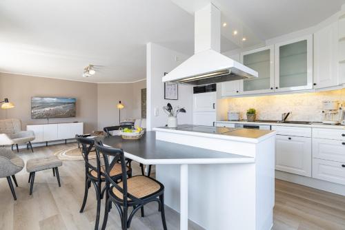 a kitchen with white cabinets and a table and chairs at Haus Baltic Flat White in Laboe