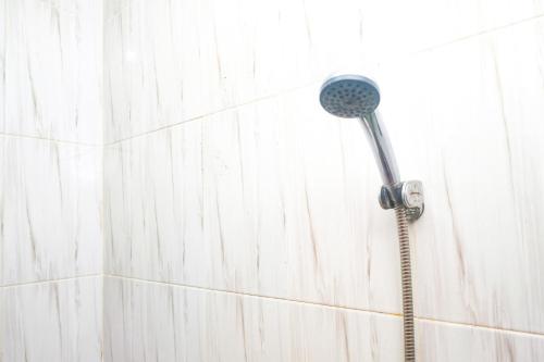 a shower with a shower head on a wall at RedDoorz @ Jalan Kedawung in Malang