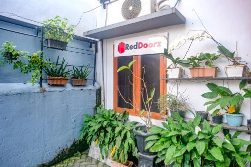 a sign on the side of a building with potted plants at RedDoorz @ Jalan Kedawung in Malang