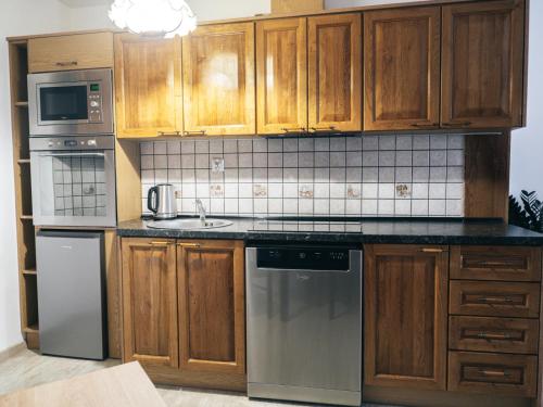 a kitchen with wooden cabinets and stainless steel appliances at Dżem's Apartaments in Lidzbark Warmiński
