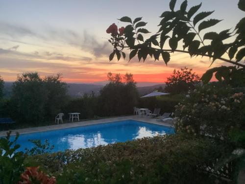 a swimming pool with a sunset in the background at Le Macchie in Baschi