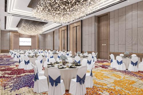 a ballroom with tables and chairs in a room with chandeliers at Vivanta Thane LBS Road in Thane