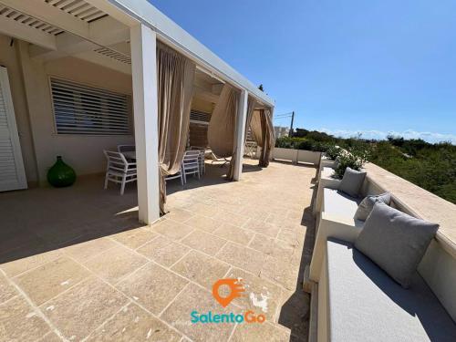a patio with chairs and tables on a house at Stanze VILLA DEL CONTE a Punta Prosciutto by SalentoGo in Punta Prosciutto