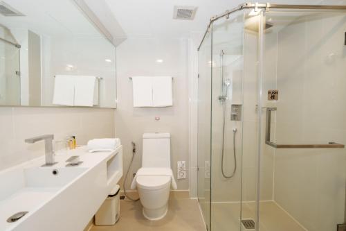 a bathroom with a toilet and a glass shower at Marvin Suites Hotel in Bangkok