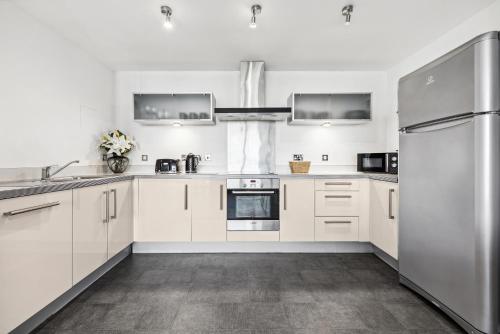 a kitchen with white cabinets and stainless steel appliances at Cotels at Vizion Serviced Apartments, Superfast Broadband, Central Location, Free Parking, Fully Equipped Kitchen in Milton Keynes