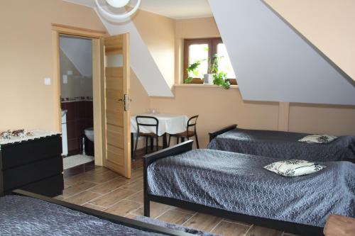 a bedroom with two beds and a table and a window at Pokoje Gościnne Сisza in Białowieża