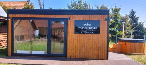 a small wooden building with a sign on it at Pensjonat Kwiatkowski apartament nr 4 in Nowęcin