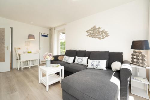 a living room with a gray couch and a table at Zur lachenden Möwe in Grömitz