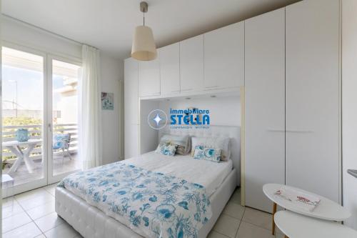 a white bedroom with a bed and a balcony at Residence Maricel in Lido di Jesolo