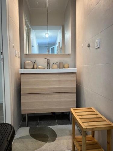 La salle de bains est pourvue d'un lavabo avec un miroir et un tabouret. dans l'établissement La Villa Blanche, à Andernos-les-Bains