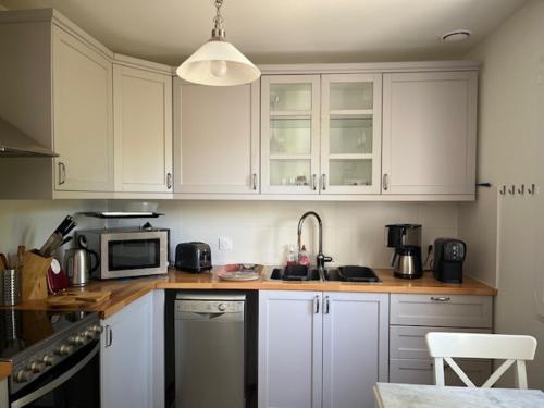 une cuisine avec des armoires blanches et un micro-ondes dans l'établissement La Villa Blanche, à Andernos-les-Bains