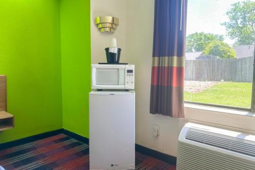 a microwave on top of a refrigerator next to a window at Classic Inn By Townhouse American Way Memphis I 240 in Memphis