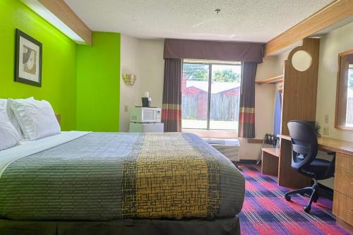 a hotel room with a bed with a green wall at Classic Inn By Townhouse American Way Memphis I 240 in Memphis
