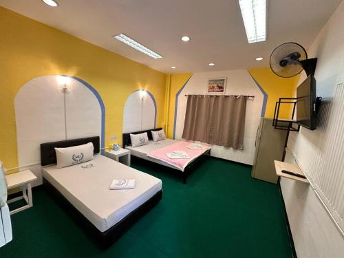 two beds in a room with green and yellow walls at Miracle Gallery Hotel in Makkasan