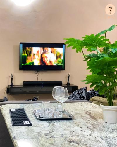 a living room with a table with a wine glass and a tv at La Luna Homes in Blantyre