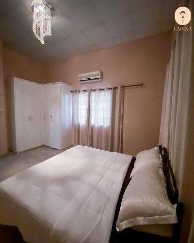 a large white bed in a bedroom with a chandelier at La Luna Homes in Blantyre