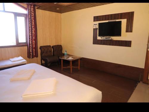 a hotel room with a bed and a tv on the wall at Hotel Sita Inn in Shimla