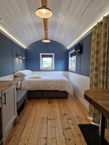 a bedroom with a bed and a blue wall at Oak Moor Shepherd Hut - Brecon Beacons, LD3 7TD in Tal-y-llyn
