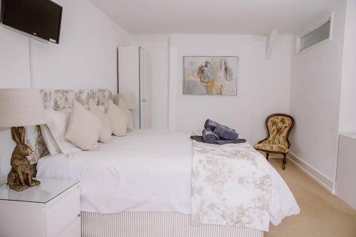 a white bedroom with a bed and a chair at Farmhouse in the heart of the New Forest in Beaulieu