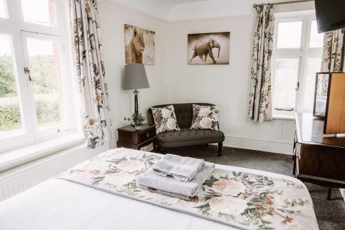 a bedroom with a bed and a chair and windows at Farmhouse in the heart of the New Forest in Beaulieu