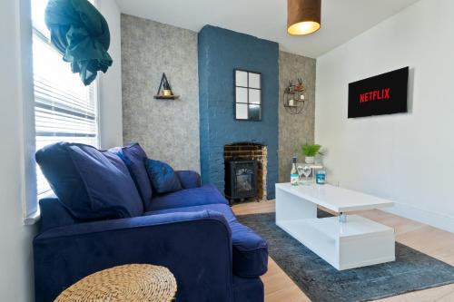 ein Wohnzimmer mit einer blauen Couch und einem Kamin in der Unterkunft Spacious Cosy City Centre House - Perfect for Contractors & Work in Gillingham