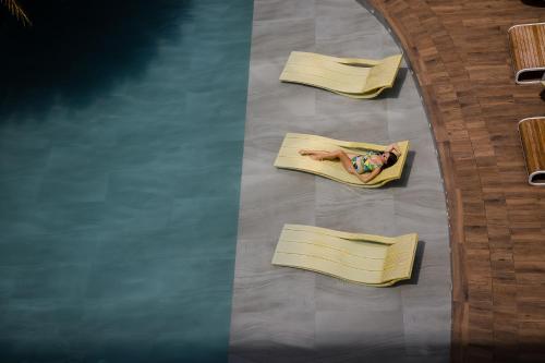 a woman laying on a bed next to a pool at Astoria Current in Boracay