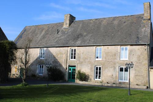an old stone building with a green door at Domaine Des Piéris - Chambres d'Hôtes in Grandcamp-Maisy