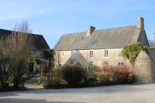 a large stone building with a gray roof at Domaine Des Piéris - Chambres d'Hôtes in Grandcamp-Maisy