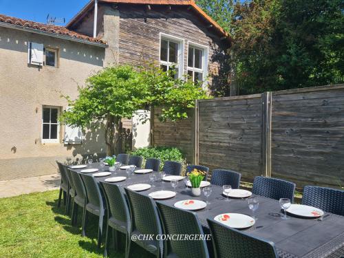 une longue table avec des chaises dans une cour arrière dans l'établissement Le Hameau 2 gîtes pour 15 personnes nature et rivière proche du Puy duFou, à La Forêt-sur-Sèvre