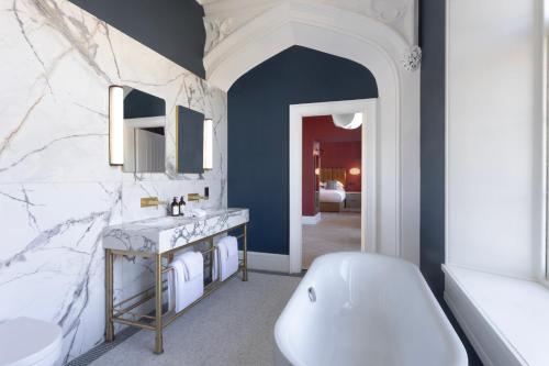 a bathroom with a white tub and a sink at JA Mar Hall Scotland in Bishopton