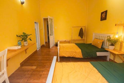 two beds in a room with yellow walls at Villa Nhà có hai cây Tùng in Bao Loc