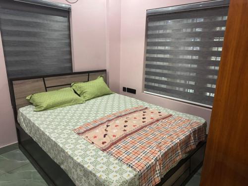 a small bedroom with a bed with green pillows at Janani Silver Apartment Chathannoor, Kottiyam in Kottiyam