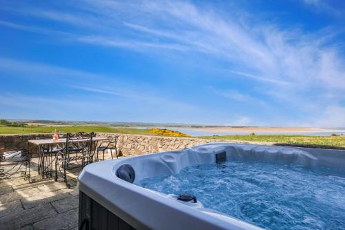 a hot tub on a patio with a view of the ocean at Budle Newton - North East Escapes in Bamburgh